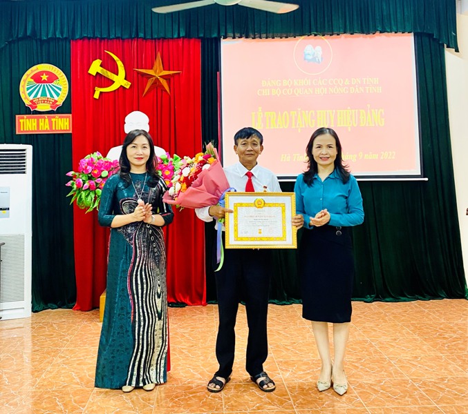 Đồng chí Nguyễn Thị Lệ Hà  và đồng chí Nguyễn Thị Mai Thủy trao Huy hiệu 40 năm tuổi Đảng và tặng hoa chúc mừng đồng chí Trần Trung Thành